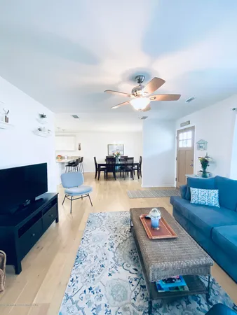 a living room with furniture and a dining table with wooden floor