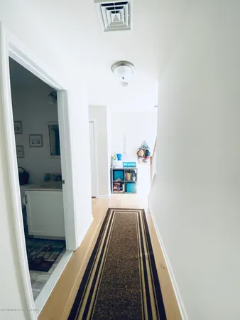 a view of a hallway with wooden floor and a bathroom