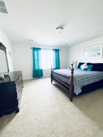 a bedroom with a bed chair and mirror