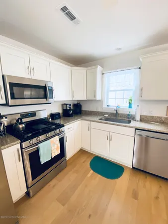 a kitchen with stainless steel appliances granite countertop a sink a stove a microwave a counter space and cabinets