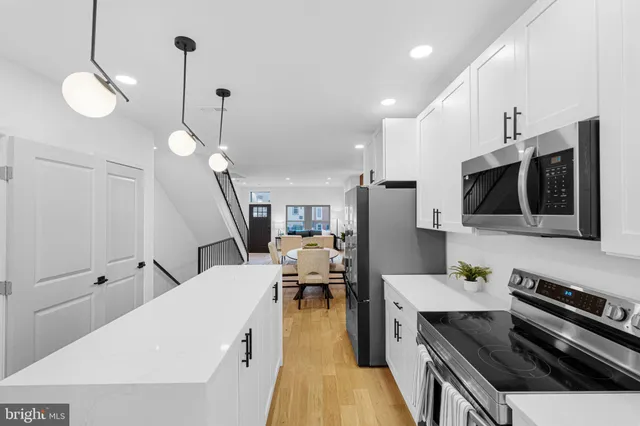 a living room with stainless steel appliances kitchen island granite countertop a stove a sink a refrigerator and a microwave