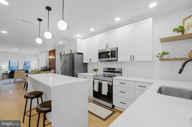 a kitchen with stainless steel appliances granite countertop a sink a stove a refrigerator cabinets and chairs