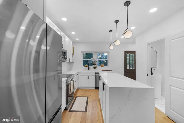 a large kitchen with stainless steel appliances lots of counter space and a chandelier