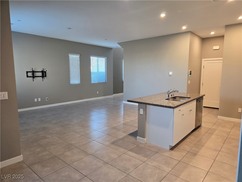 3192 Timorasso Avenue Henderson, NV 89044 - Photo 16 of 16 Kitchen with dark stone countertops, a center island with sink, light tile patterned floors, open floor plan, and white cabinets
