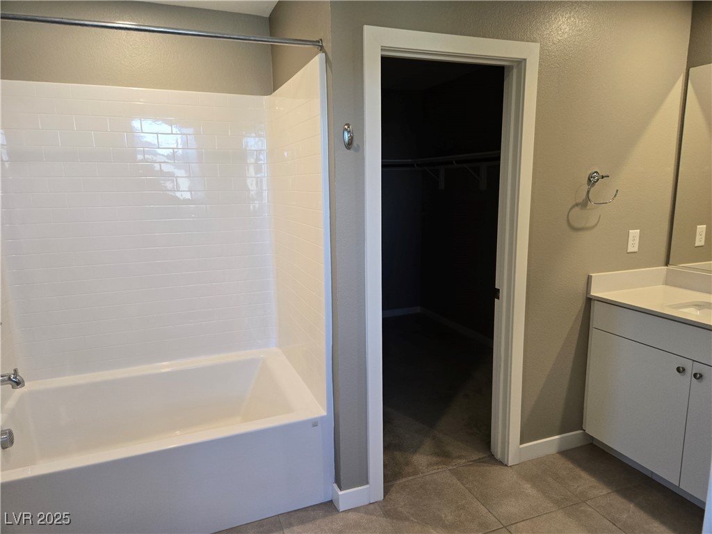 3192 Timorasso Avenue Henderson, NV 89044 - Photo 9 of 16 Bathroom with a walk in closet, light tile patterned floors, vanity, shower / tub combination, and a textured wall