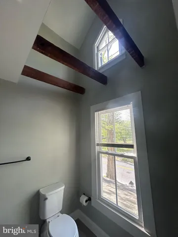 a white toilet sitting next to a window in a bedroom