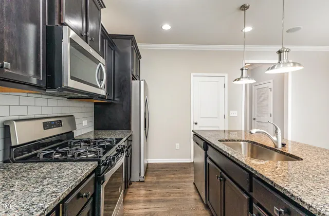 a kitchen with granite countertop a sink stainless steel appliances and cabinets