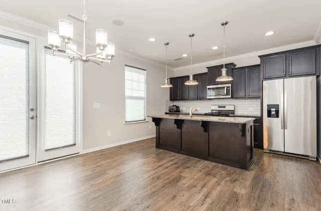 a kitchen with kitchen island granite countertop wooden floors stainless steel appliances a sink and a window