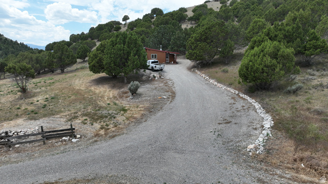 2006 Swenson Valley Road Bancroft, ID 83217 - Photo 18 of 51 Gravel driveway leading to a secluded residence nestled into a hillside, surrounded by mature evergreen trees and natural landscaping