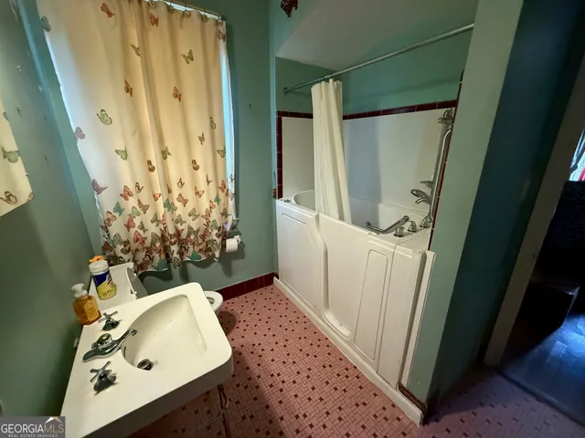 a bathroom with a sink and mirror with bathtub
