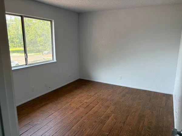 an empty room with wooden floor and windows