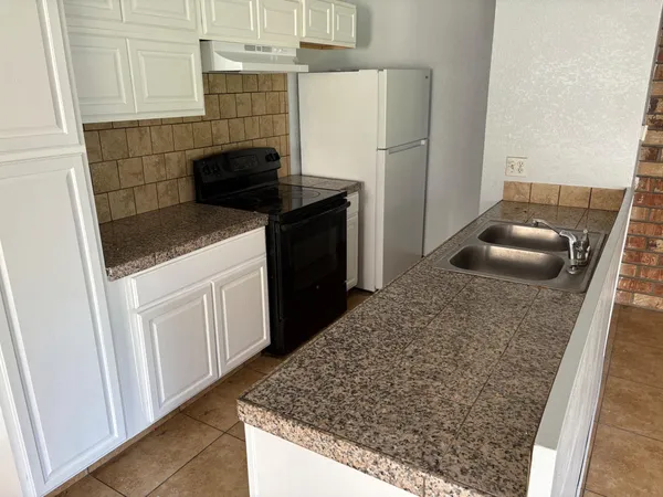 a kitchen with granite countertop a sink and a stove