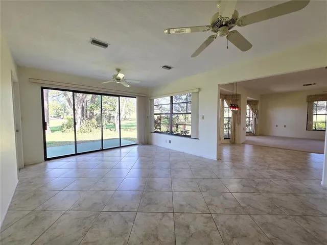 a view of an empty room with a window and a kitchen view