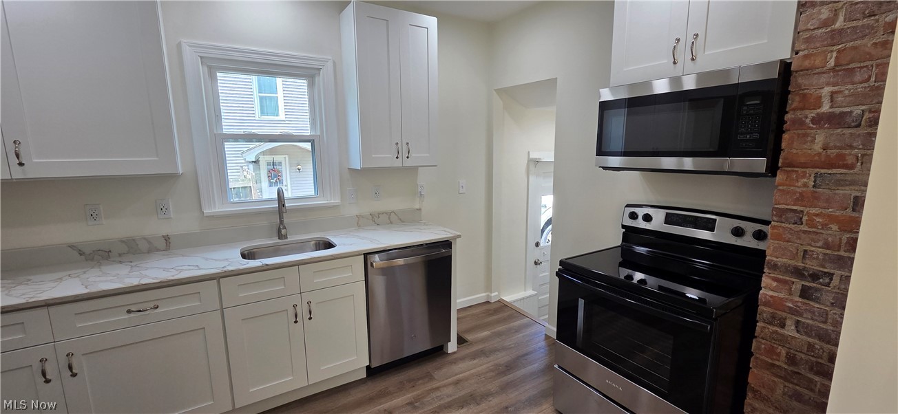 9964 East River Road Elyria, OH 44035 - Photo 14 of 45 All new kitchen featuring white shaker cabinetry, stainless steel appliances, wood-finish flooring, white countertops, and an exposed brick accent wall
