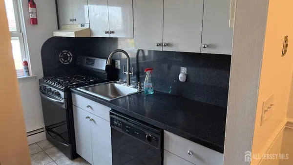 a kitchen with granite countertop white cabinets and black appliances