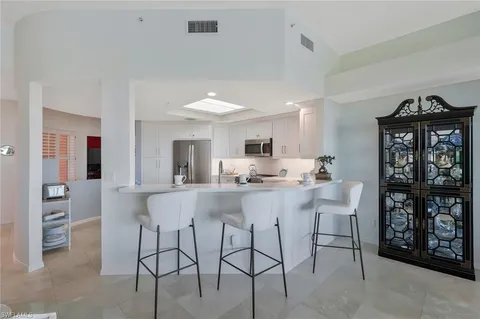 a kitchen with stainless steel appliances kitchen island granite countertop a dining table chairs and a refrigerator
