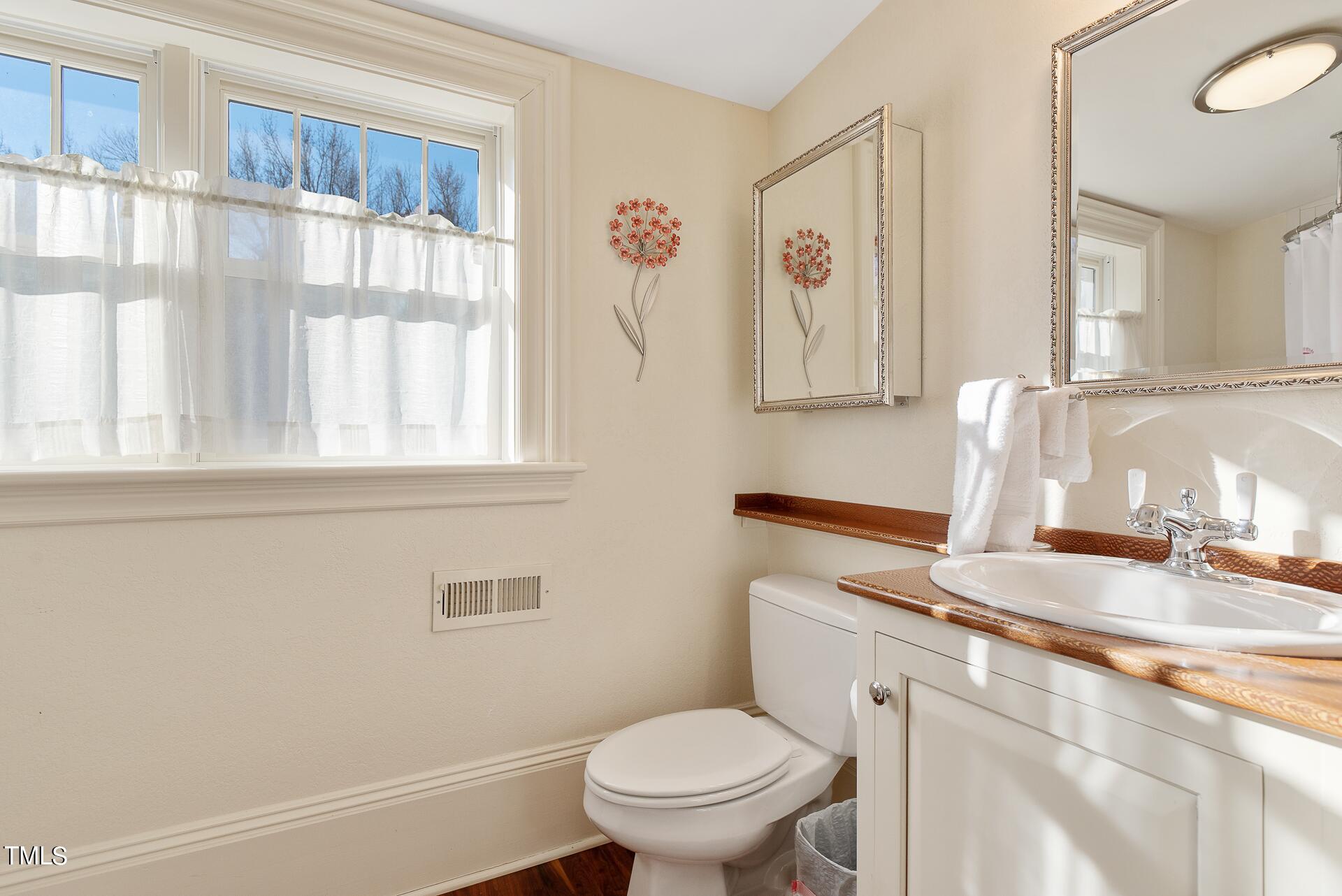 5612 Cabe Ford Road Durham, NC 27705 - Photo 31 of 42 a bathroom with a granite countertop sink a toilet and a window