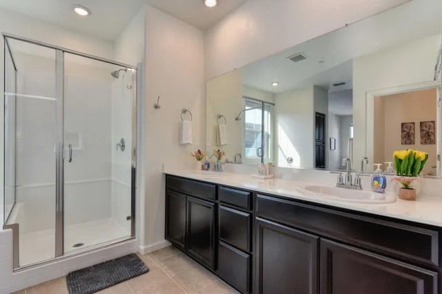 a bathroom with a double vanity sink mirror and shower
