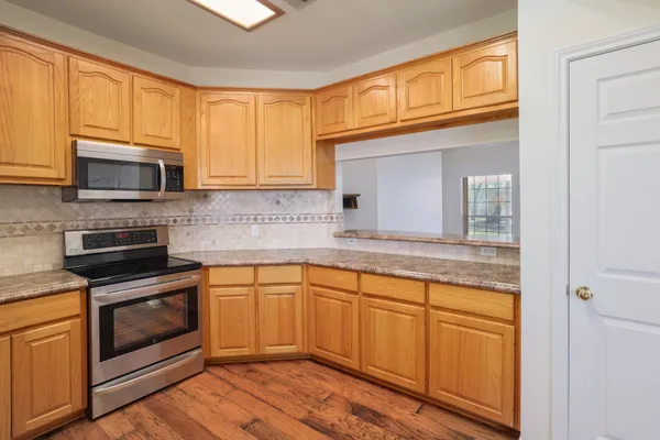a kitchen with granite countertop cabinets stainless steel appliances and wooden floor