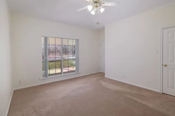 an empty room with a chandelier fan and windows