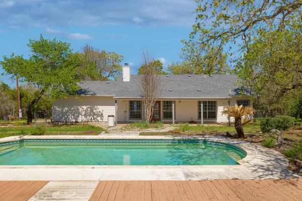 a front view of a house with garden and trees