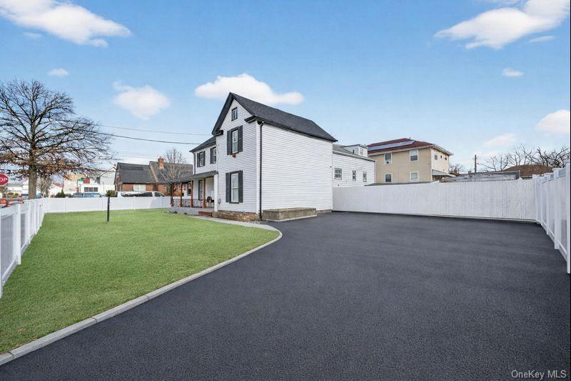 136-03 220th Street Queens, NY 11413 - Photo 3 of 27 a view of a white house with a big yard and a large tree