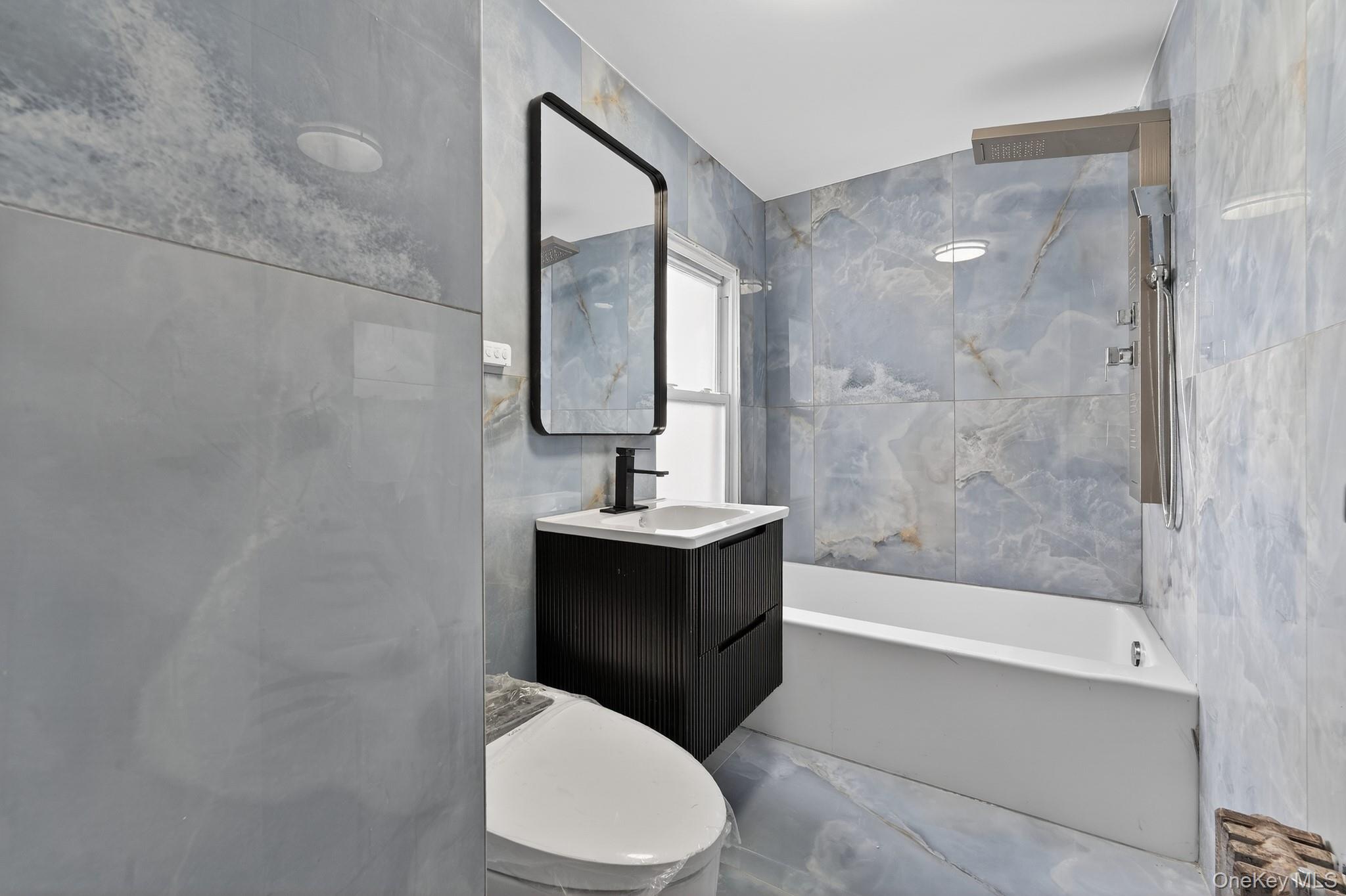 136-03 220th Street Queens, NY 11413 - Photo 6 of 27 a bathroom with a bathtub shower sink mirror and toilet