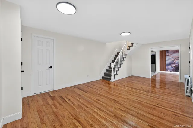 a view of an empty room with wooden floor and stairs