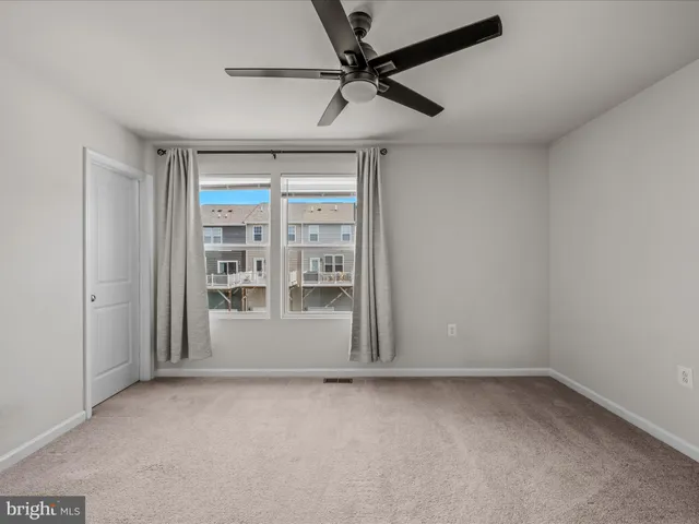 an empty room with a ceiling fan and window