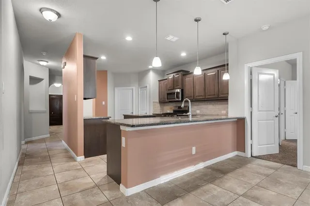 a large kitchen with kitchen island a refrigerator a counter top and wooden floor