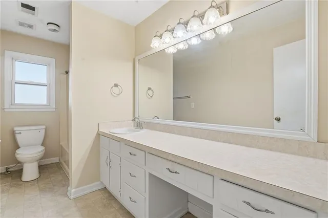 a spacious bathroom with a granite countertop sink a toilet and a mirror