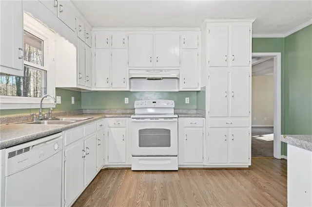 a kitchen with granite countertop white cabinets and white stainless steel appliances