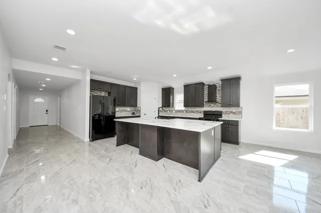 a large white kitchen with kitchen island a sink stainless steel appliances and cabinets