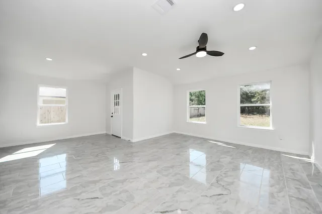 an empty room with a window and a ceiling fan