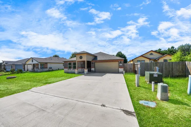 a view of a house with a big yard potted plants and large tree