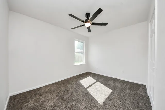 an empty room with a window and a ceiling fan