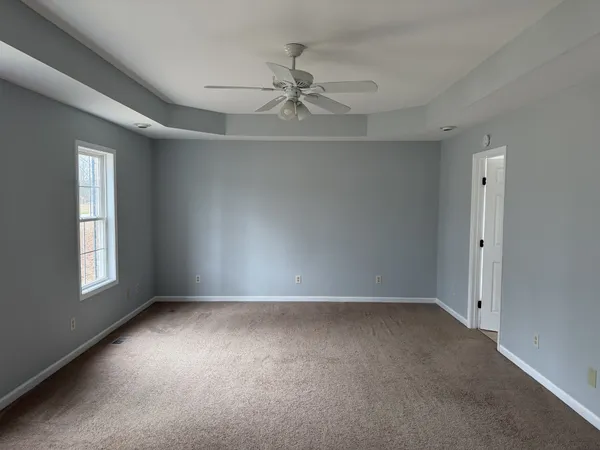 an empty room with a ceiling fan and window