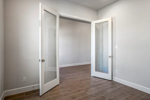 an empty room with wooden floor and windows