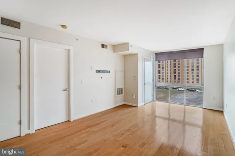 a view of an empty room with wooden floor and a window