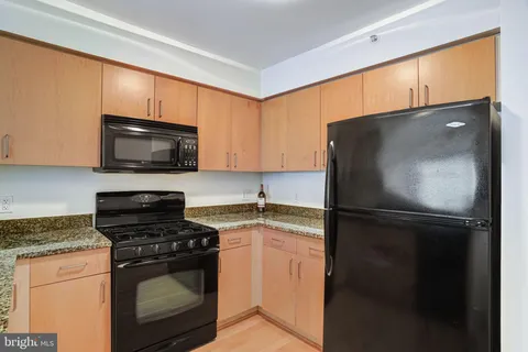 a kitchen with granite countertop a refrigerator stove and microwave