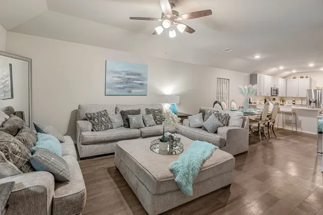 a living room with furniture and a view of kitchen