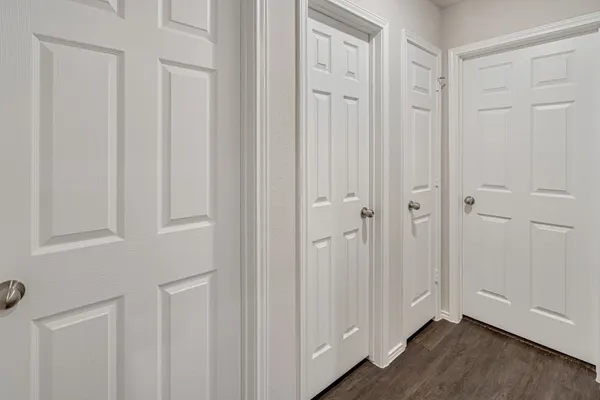 a view of a hallway with wooden floor and a bathroom