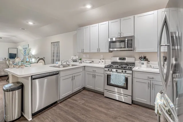 a kitchen with kitchen island granite countertop a sink cabinets and stainless steel appliances