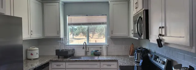 a kitchen with stainless steel appliances granite countertop a sink a stove and a refrigerator