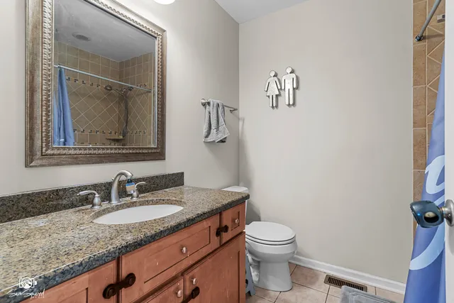 a bathroom with a granite countertop sink vanity mirror and toilet