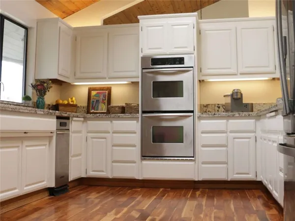 a kitchen with granite countertop white cabinets and white appliances