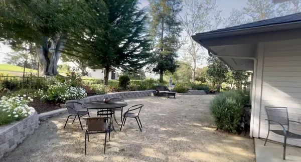 a view of backyard with table and chairs and potted plants