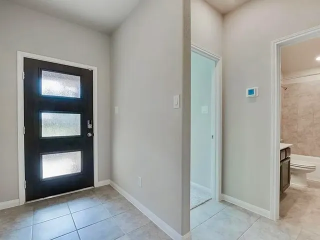 a view of an empty room and bathroom with a mirror