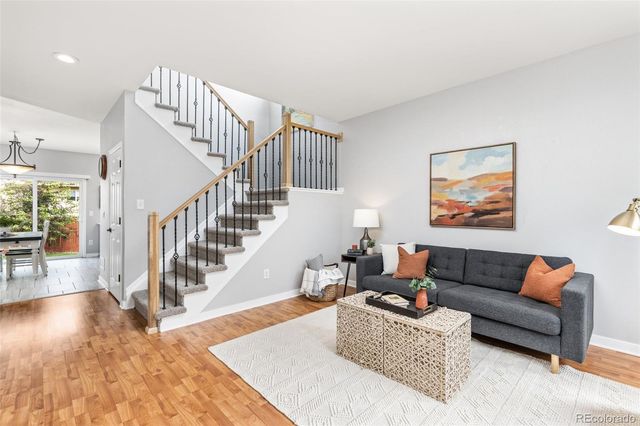 a living room with furniture and stairs with wooden floor