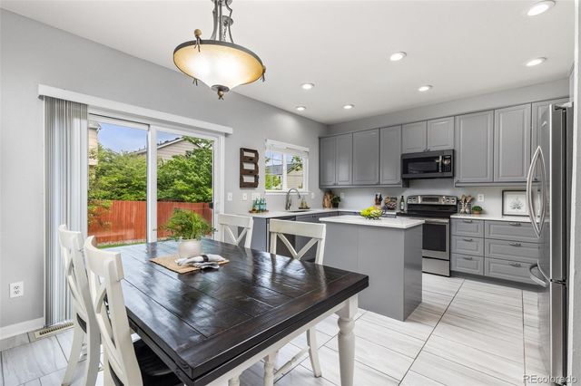 a kitchen with kitchen island granite countertop a stove a sink a microwave dining table and chairs